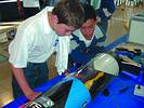 Two participants test a model racing car in a wind tunnel to assess its aerodynamics